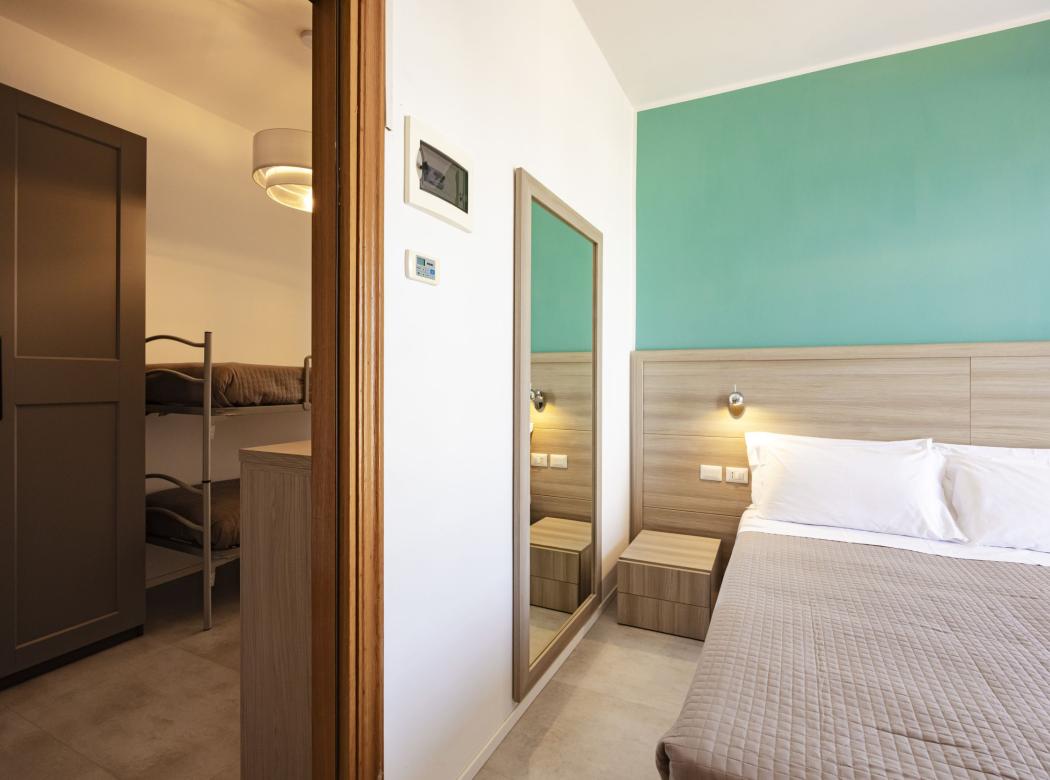 Cozy room with a double bed and bunk beds, relaxing atmosphere.