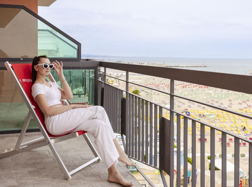 Relaxed woman on terrace, sea view, summer and serene atmosphere.
